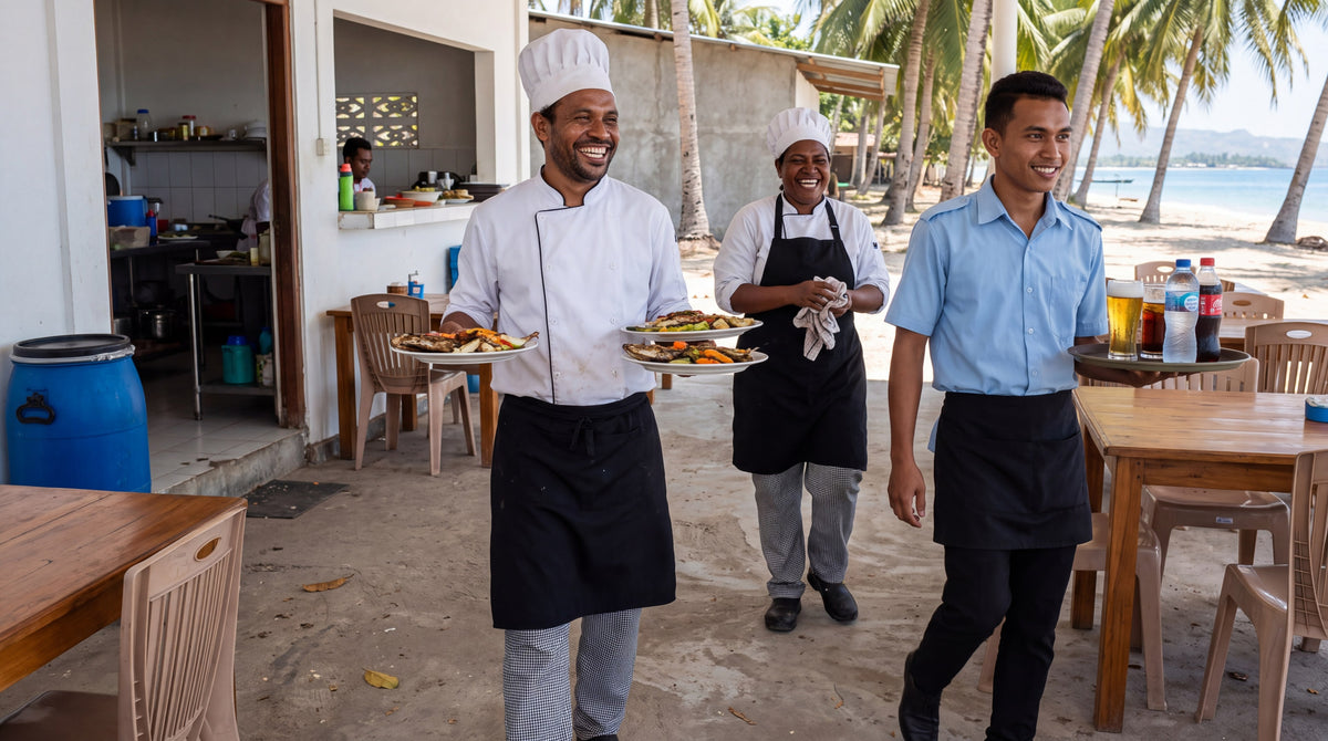 Chefs in white Al Dente jackets and black bib aprons with a waiter in a blue Epaulette shirt on a beachside terrace