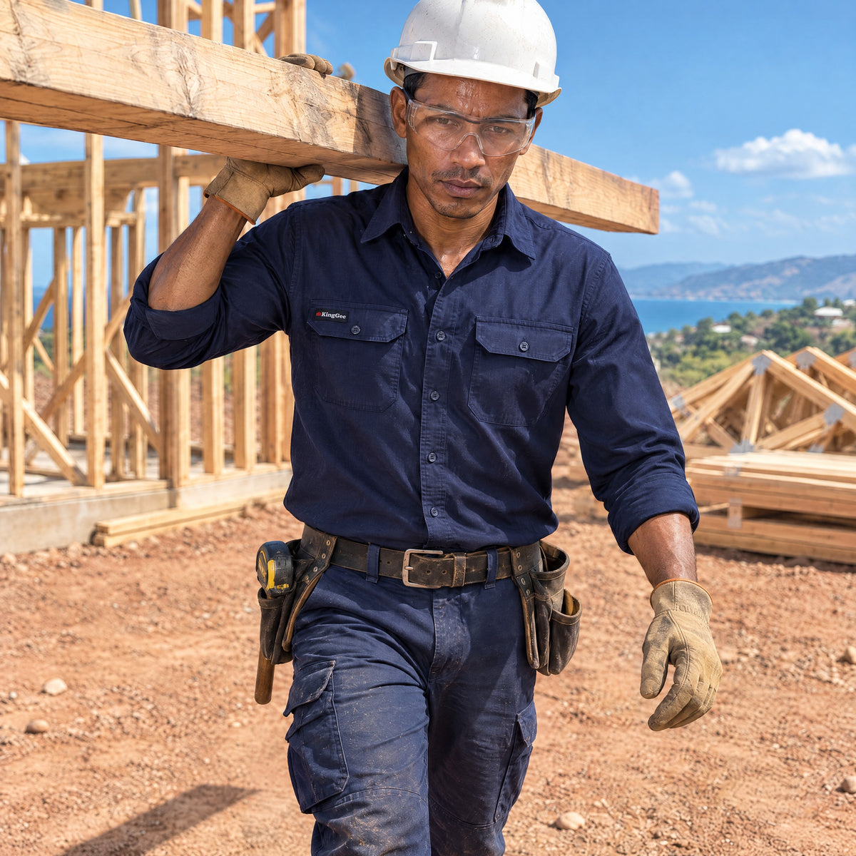 Carpenter carrying a timber beam in a navy KingGee Workcool Pro work shirt