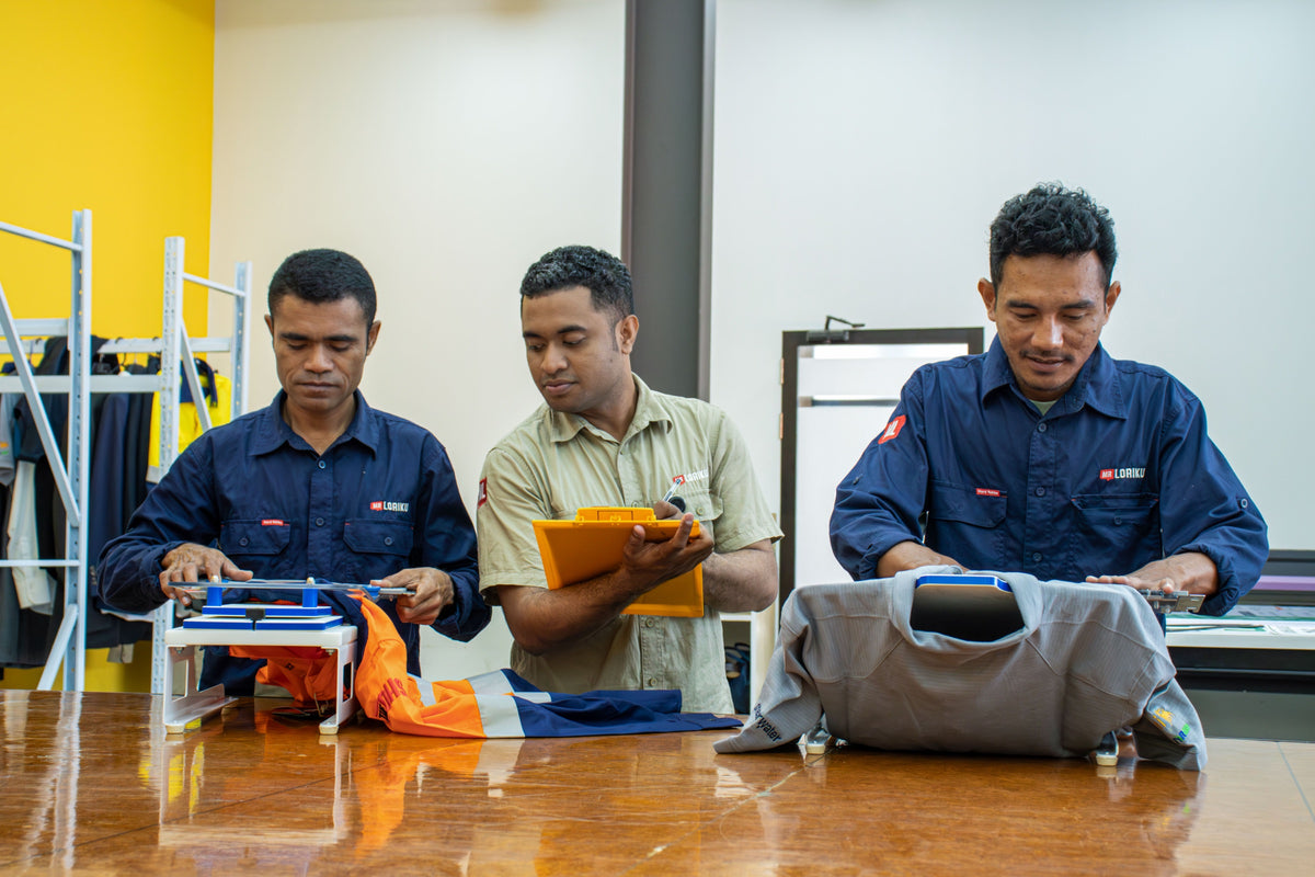 Mr. Loriku team hooping uniforms for embroidery at the Dili workshop