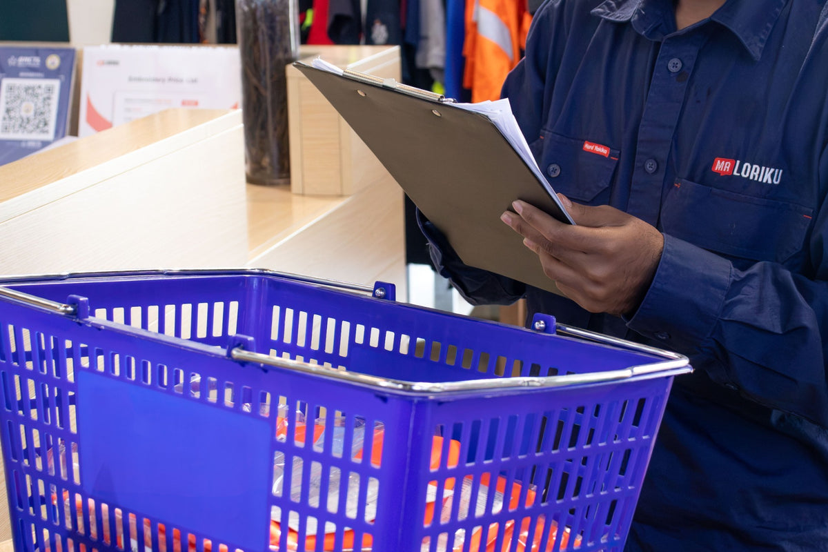 Mr. Loriku staff member checking a team order list on a clipboard next to a basket of hi vis gear